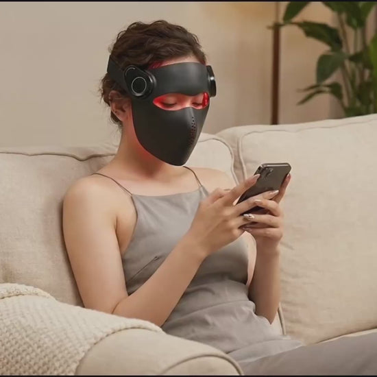 Woman relaxing on a sofa while wearing the black Kivorla 4-Wavelength Red Light Therapy Mask