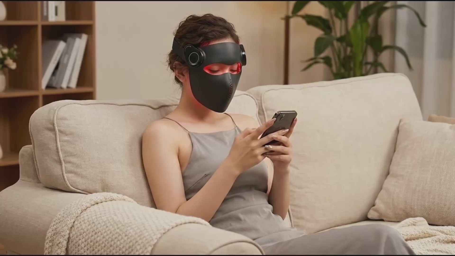 Woman relaxing on a sofa while wearing the black Kivorla 4-Wavelength Red Light Therapy Mask